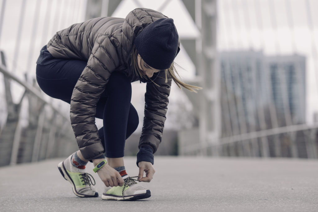 Frau steht auf Brücke und bindet Sneaker