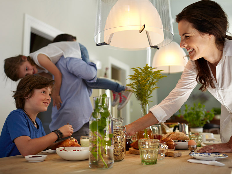 Familie sitzt am Frühstückstisch mit Philips Hue Lampen, steuerbar über den Google Assistant
