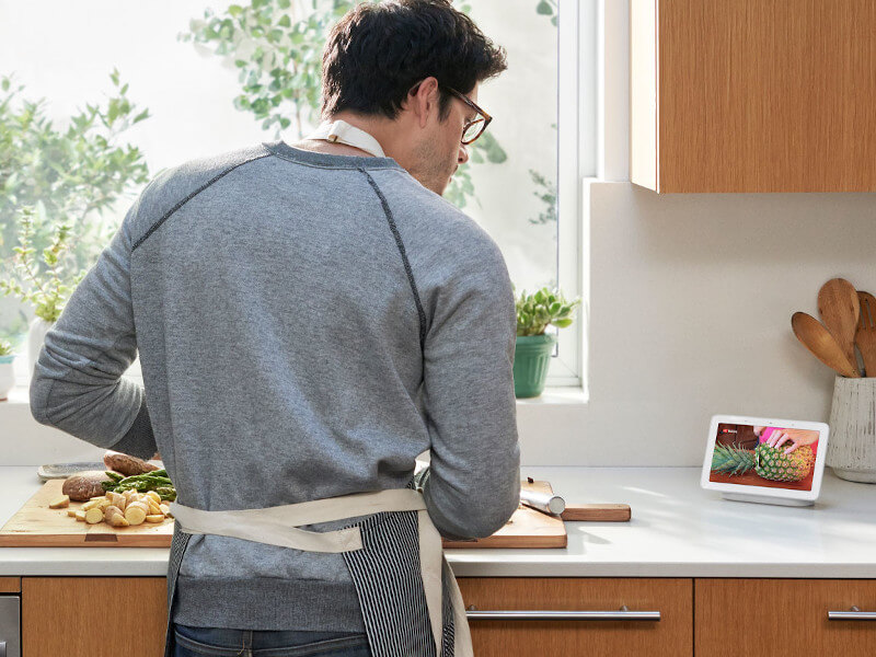 Ein Mann steht in der Küche und lässt sich ein Kochvideo auf dem Google Nest Hub abspielen