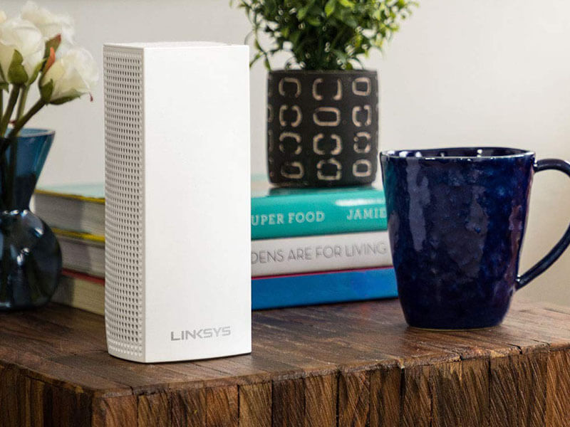 Das Linksys Velop Tri-Band Mesh-WLAN-System auf einem Tisch neben einer Tasse