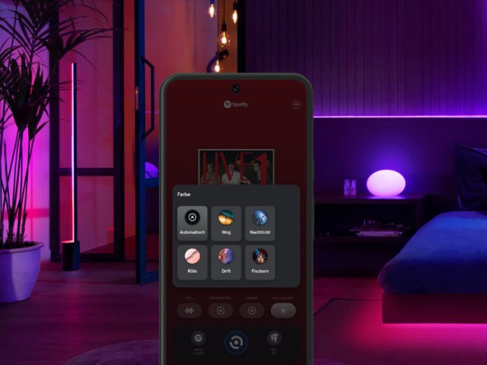 Philips Hue Sync & Spotify verknüpfen: Schlafzimmer mit Hue-Beleuchtung in Blau-, Rot- und Lilatönen, App im Vordergrund zeigt abgespielte Musik und auswählbares Farbschema
