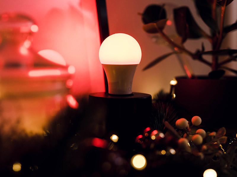 LEDVANCE Smart Home Glühbirne in rotem Licht neben weihnachtlicher Deko