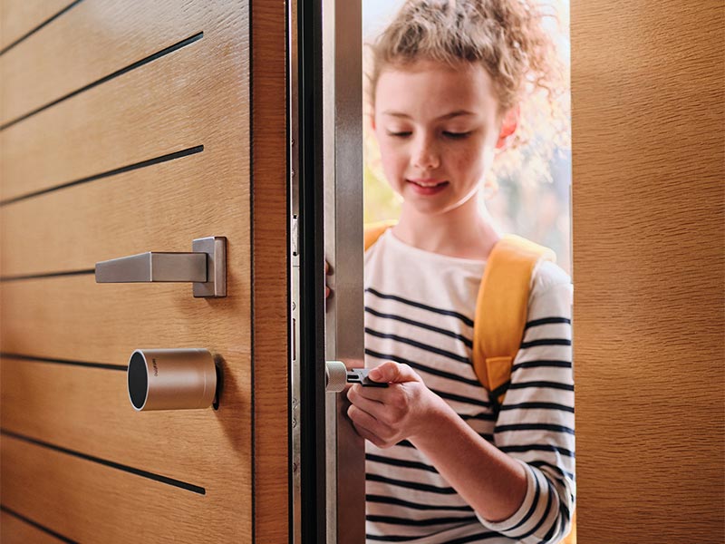 Netatmo Smartes Türschloss - Mädchen schließt die Tür mit smartem Schlüssel auf