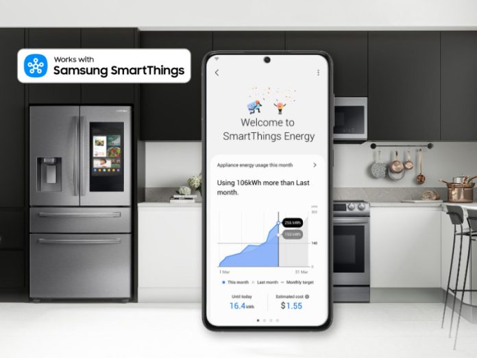 Samsung SmartThings Energy Dashboard auf Smartphone-Bildschirm, Küche mit Samsung-Kühlschrank im Hintergrund