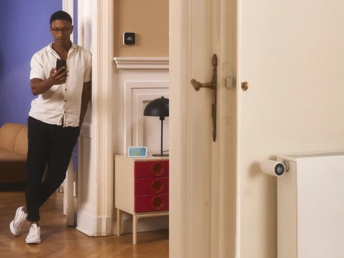 tado° zeigt falsche Temperatur: Mann schaut auf Smartphone, in einem Raum hängt ein tado° Funk-Temperatursensor, im anderen ein Heizkörperthermostat.