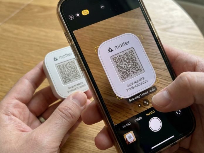 Hände scannen den QR-Code auf einem weißen Matter-Gerät mit einem Smartphone, um Matter zu installieren. Das Matter-Logo und die Seriennummer sind auf dem Bildschirm sichtbar. Der Kontext ist die Einrichtung eines Matter-Smart Homes.