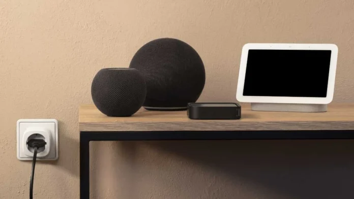 Eve Energy Smart Plug in einer Steckdose, daneben auf einem Tisch eine Auswahl an Thread Border Routern: HomePod Mini, Amazon Echo, Google Nest Hub