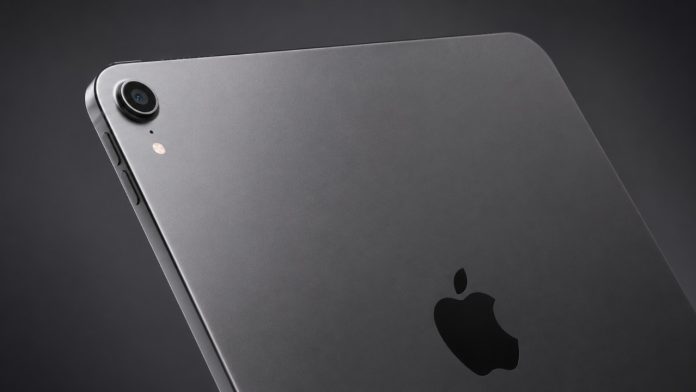 Eine Nahaufnahme der Rückseite eines spacegrauen iPads, auf der das glänzende schwarze Apple-Logo und das Kameramodul vor einem dunkelgrauen Hintergrund deutlich zu erkennen sind.