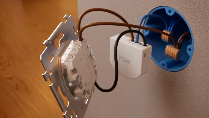 Ein weißes Philips Hue-Wandschaltermodul, das an die elektrische Verkabelung eines Lichtschalters in einer blauen Unterputzdose angeschlossen ist.