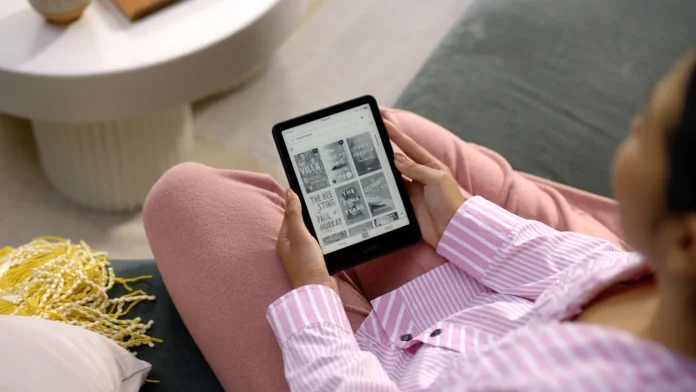 Eine Person in rosa Kleidung sitzt auf der Couch und stöbert auf einem Kindle in einer digitalen Bibliothek, was dabei hilft, den richtigen E-Reader für optimalen Lesegenuss auszuwählen.