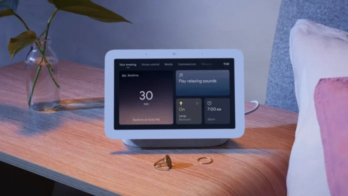 Ein Google Nest Hub Smart Display auf einem Nachttisch aus Holz zeigt die Abendroutine und die Weckereinstellungen neben einer Glasvase mit einer Pflanze an.