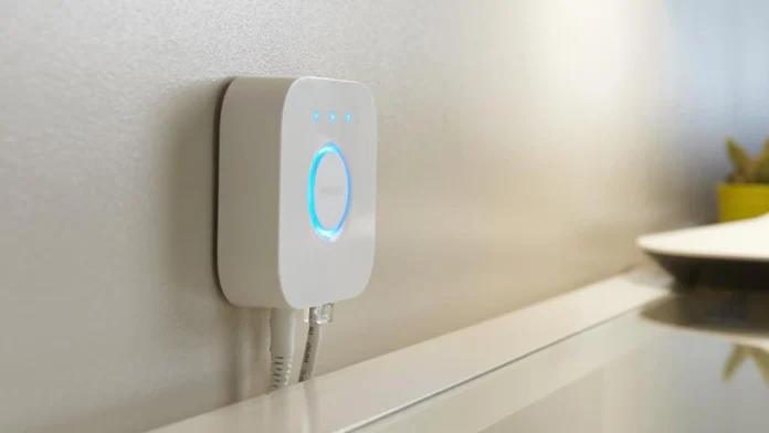 Philips Hue Bridge an der Wand über einem Glastisch mit weißem Metallrahmen
