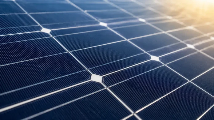 Nahaufnahme moderner blauer Solarmodule, auf deren Oberfläche sich das warme Sonnenlicht spiegelt.