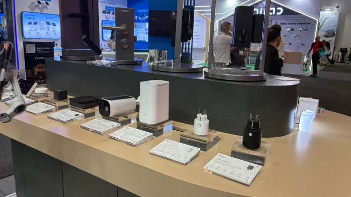 Aqara-Smart-Home-Geräte, darunter Sicherheitskameras, Hubs und intelligente Steckdosen, werden auf einer Technologiemesse ausgestellt.