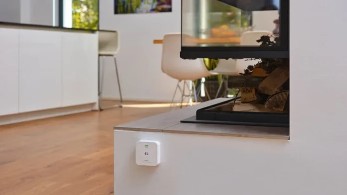 Weißes CO₂-Messgerät an der Wand in einem modernen Interieur neben einem Kamin.