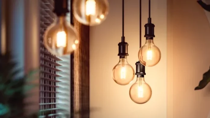Drei dekorative Philips Hue-Filamentlampen hängen an schwarzen Kabeln und verbreiten in einem modernen Interieur einen warmen, stimmungsvollen Schein.