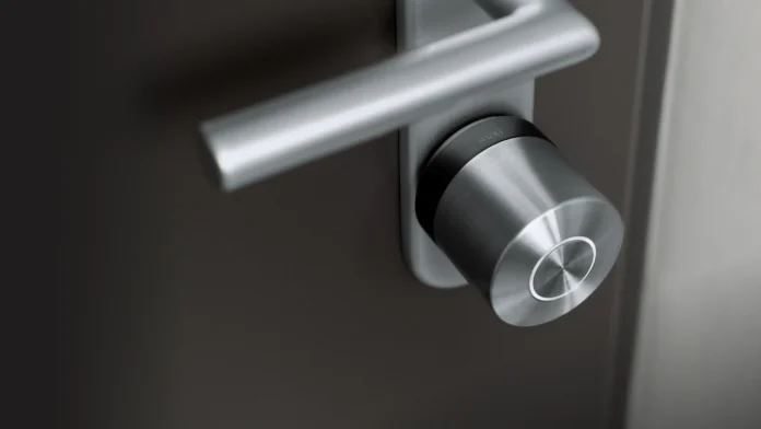 Ein modernes silbernes Türschloss, montiert an einer dunklen Tür – für alle, die online ein Nuki Smart Lock