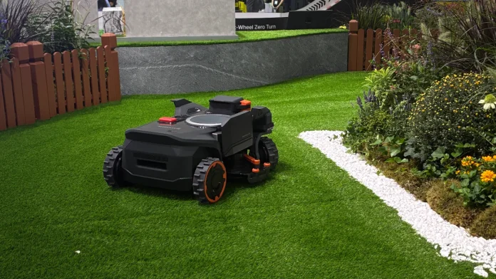 Segway Navimow H5 Pro Mähroboter fährt auf einer Demonstrationsfläche auf der IFA 2026 mit Rasen, Kiesrändern und Sträuchern in der Mitte.