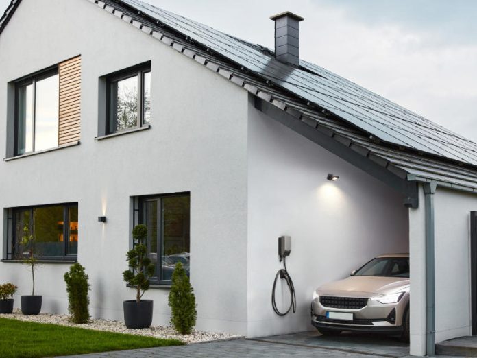 Smartes Einfamilienhaus mit PV-Anlage, Elektroauto im Carport und Wallbox an der Wand