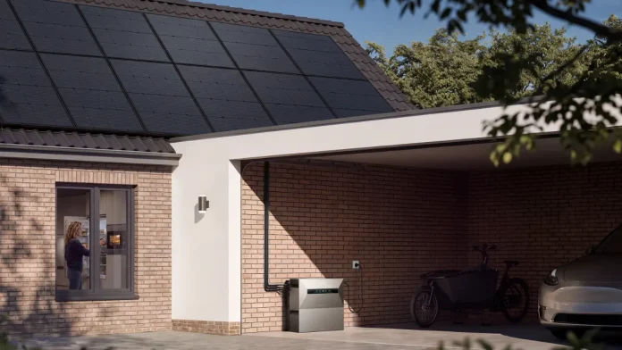 Anker SOLIX Heimspeicher in einem Carport neben einem Wohnhaus mit Solarmodulen auf dem Dach
