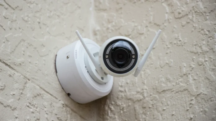 Symbolbild für eine Kamera ohne Video: weiße kabellose Überwachungskamera mit Antennen an einer verputzten Wand.