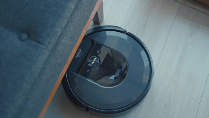 iRobot Roomba fährt unter einem Sofa über einen hellen Holzboden