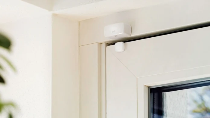 Weißer Fensterkontakt am Rahmen eines Fensters, daneben eine Zimmerpflanze