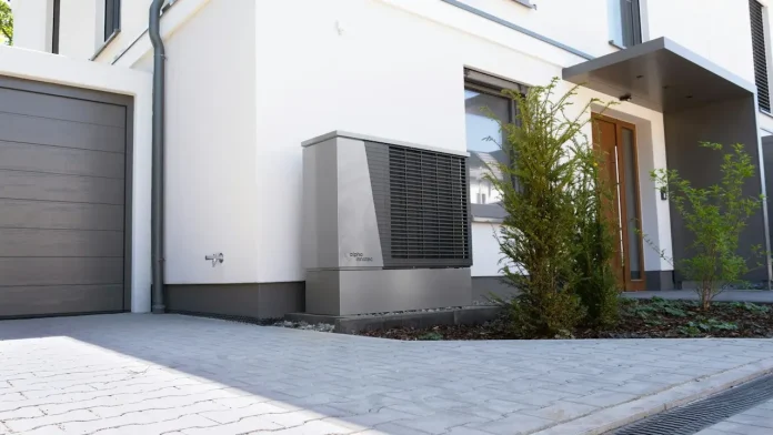 Modernes Haus mit der Außeneinheit einer Luft-Wasser-Wärmepumpe neben Garage und Haustür