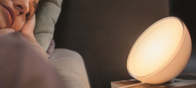 Smarte Tischleuchte auf Nachttisch neben schlafender Person im Bett